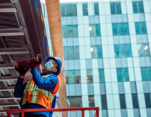 Construction worker with mask working on outside structure