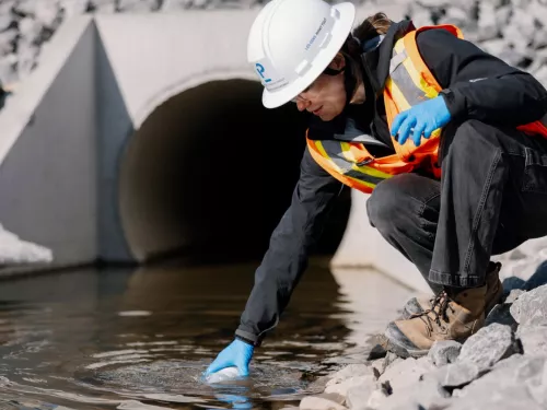 Pomerleau's Worker on a construction site in Vaudreuil, collecting water samples for environmental purposes
