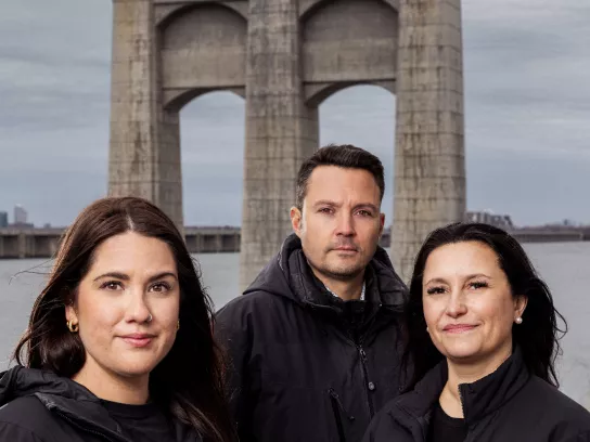 Three people in front of deconstructed bridge.