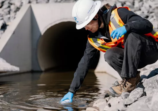 Pomerleau's Worker on a construction site in Vaudreuil, collecting water samples for environmental purposes
