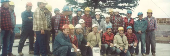 Des travailleurs et Laurette sur un chantier de construction Pomerleau dans les années 80. | Workers and Laurette at a Pomerleau construction site in the 1980s.