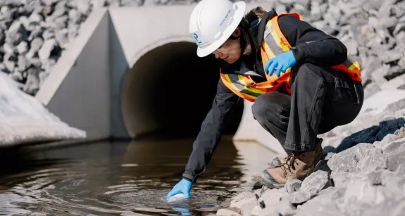 Pomerleau's Worker on a construction site in Vaudreuil, collecting water samples for environmental purposes
