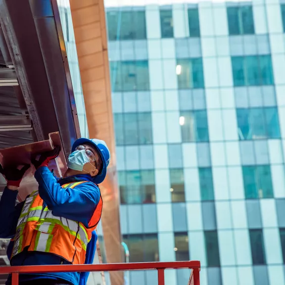 Construction worker with mask working on outside structure