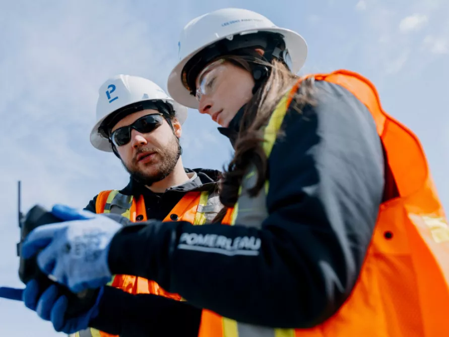 Workers on a construction site using drone technologies, an example of Pomerleau's expertise in bridges and infrastructures solutions